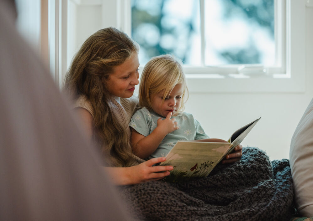 A mother reads a book to her young child.