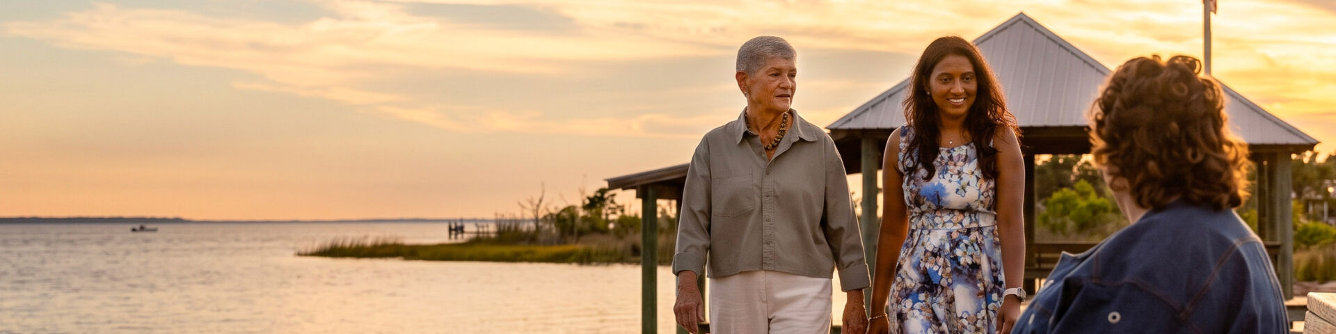 Two women walk toward a third woman while on a pier in Mobile Bay.