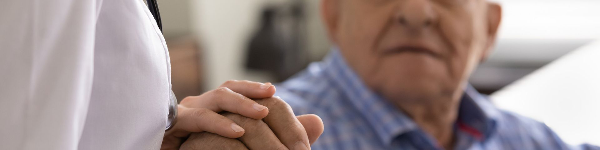 A physician holds the hand of an elderly patient.