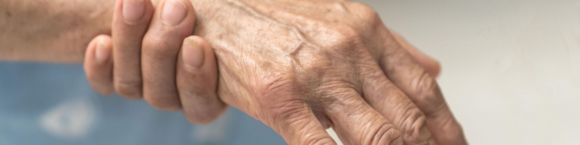 An elderly patient rubs their wrist.