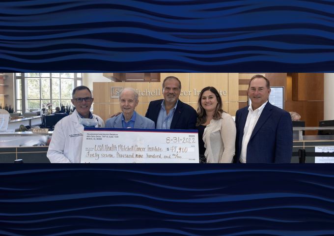 Martin Heslin, M.D., left, director of the USA Health Mitchell Cancer Institute, receives donations totaling $47,900 from Abraham A. Mitchell, second from left; and K.C. Constantine, third from left, president of Manning Inc. Piggly Wiggly. Also pictured are David White, right; and Maya De Andrade.