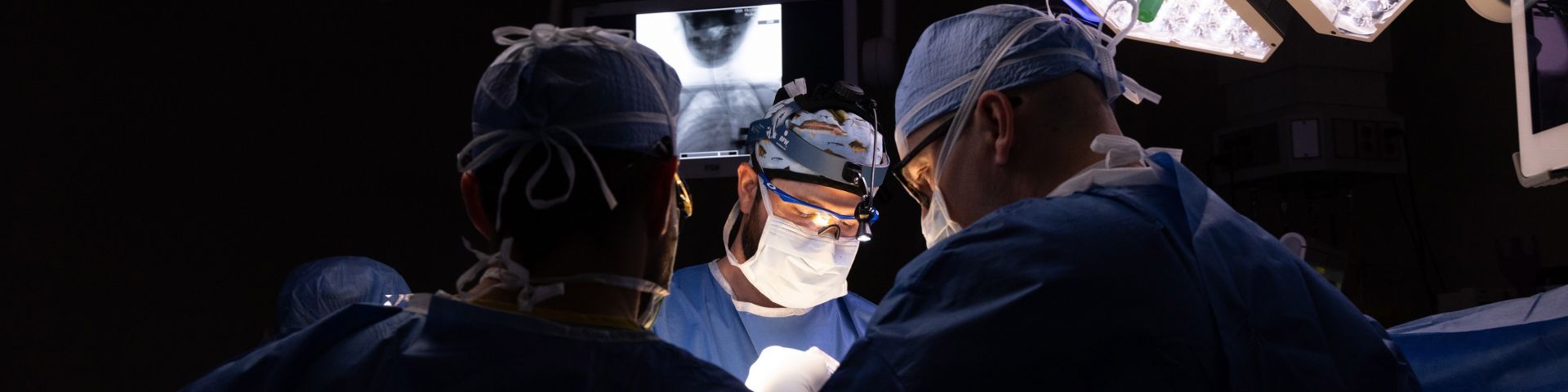 Dr. Tyler McDonald, pediatric orthopaedic surgeon and an assistant professor of orthopaedic surgery, center, and Dr. Richard Menger, chief of complex spine surgery and associate professor of neurosurgery, right, perform surgery at USA Health Children’s & Women’s Hospital in August 2023 to insert pins into Abby Flowers' skull for halo gravity traction.